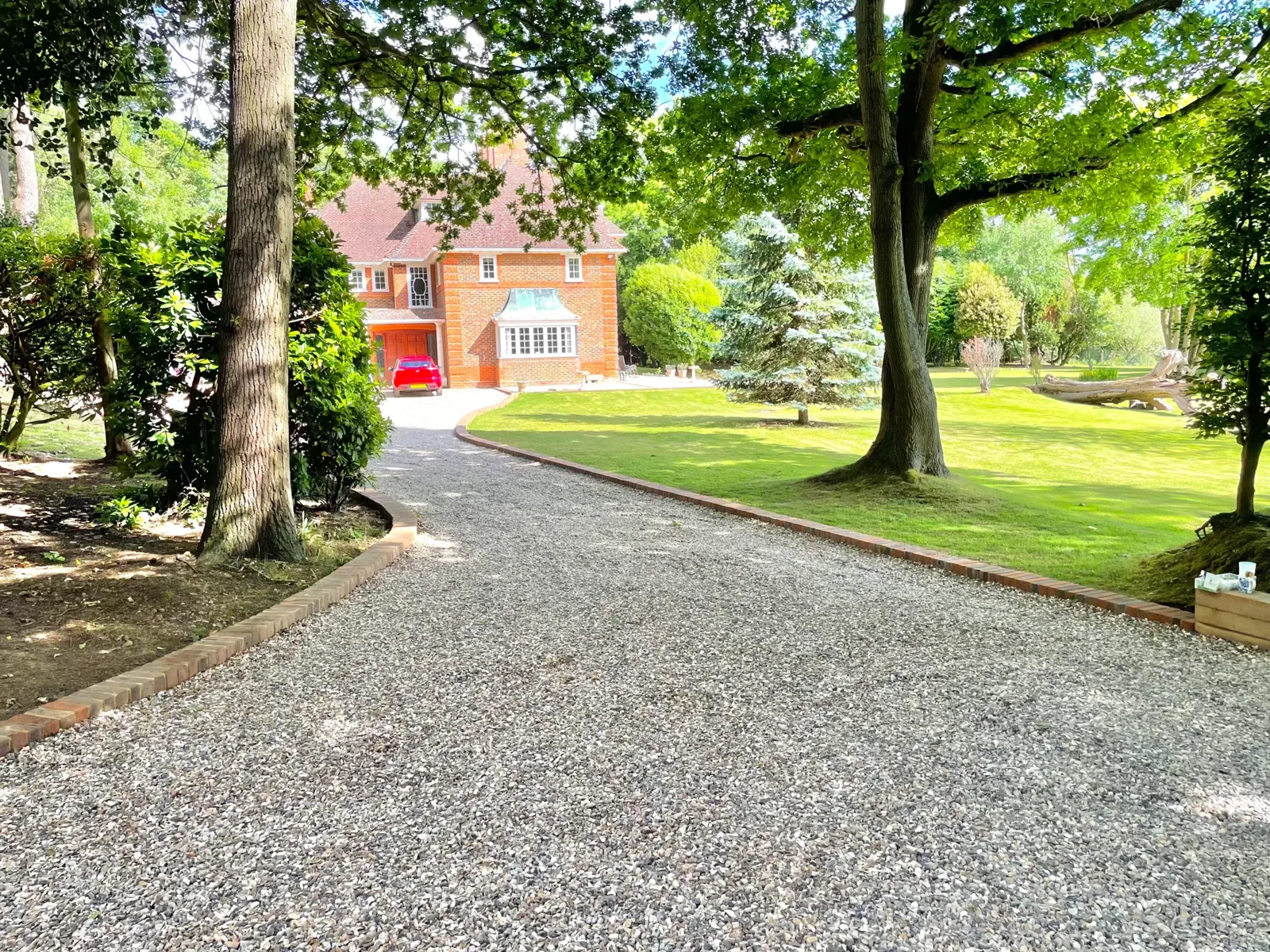 Wide gravel driveway sweeping to a double garage